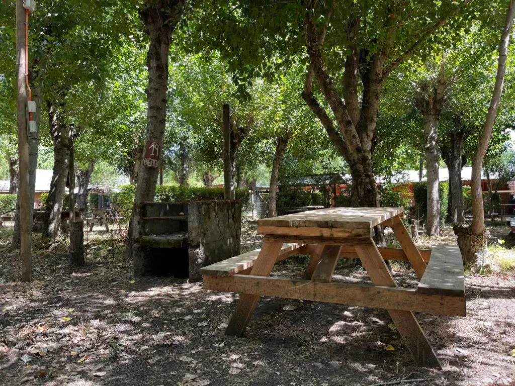 Vista panorámica del río en Camping San José, con puente de madera y sauces llorones en Salto del Laja